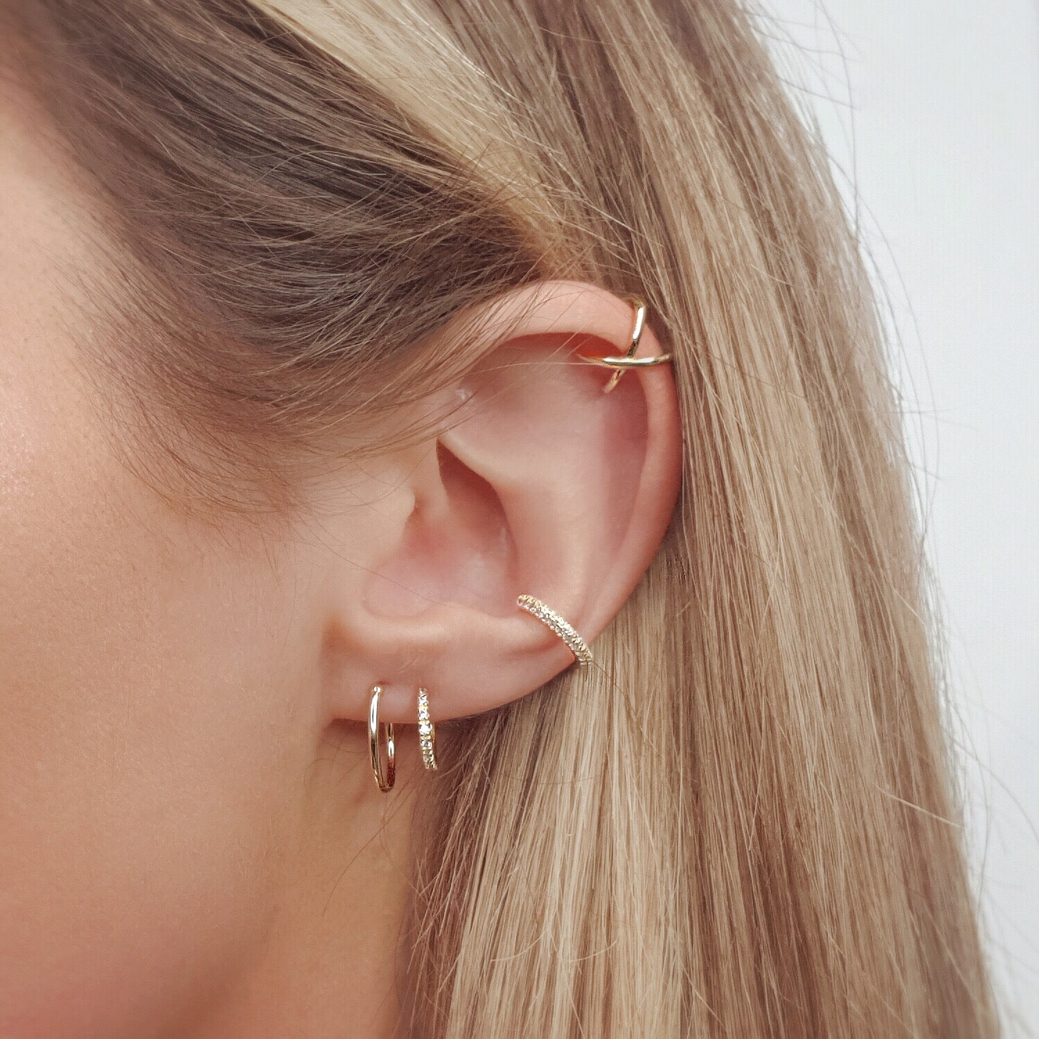 Sparkly gold plated cubic zirconia ear cuff with multiple Riptide 5 earrings, including gold plated double hoop earrings and gold plated criss cross ear cuff